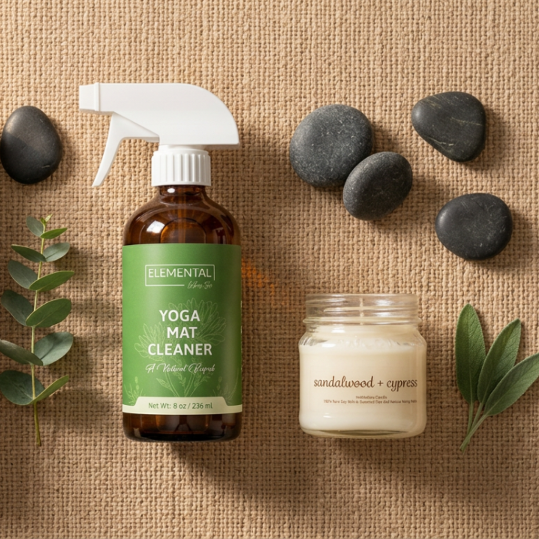 Yoga mat cleaner bottle, candle, and stones on a textured surface
